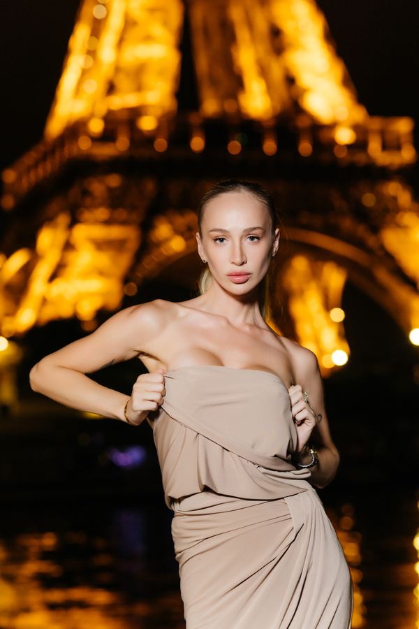 Portrait of a woman in beige strapless draped dress, Eiffel Tower, Paris at night