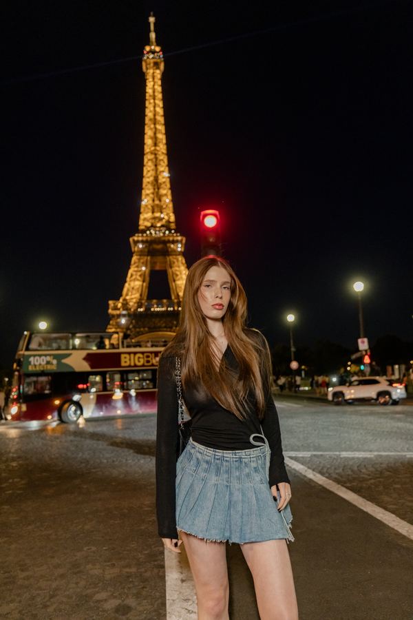 Portrait of a woman in black top, denim pleated skirt, Eiffel Tower, Paris at night