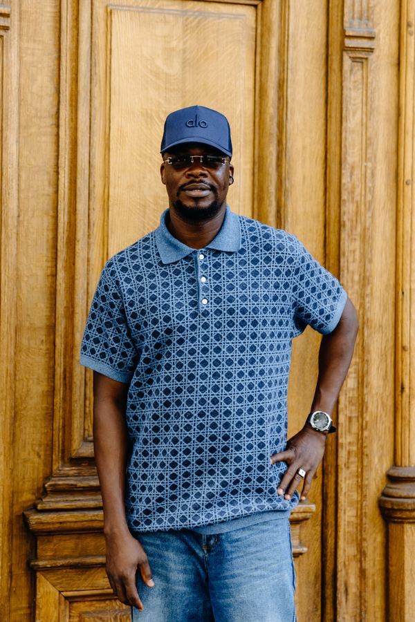Portrait of a man in blue patterned knit polo, navy cap, sunglasses, Paris