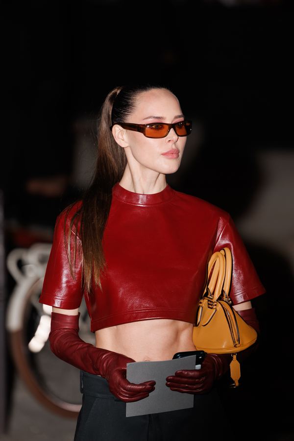 Street style at Paris Fashion Week: red leather cropped top, long red gloves, tan handbag, orange sunglasses, show venue entrance, Paris at night