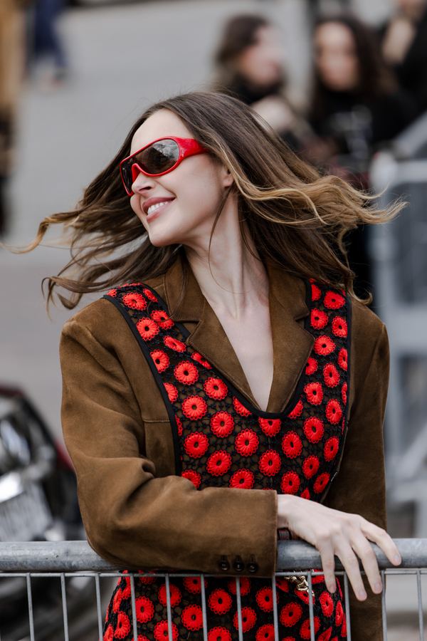 Street style at Paris Fashion Week: brown leather jacket, red and black poppy-print top, red sunglasses, show venue entrance, Paris