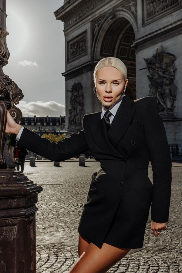 Portrait of a woman in black blazer dress, tie, Arc de Triomphe, Paris at golden hour
