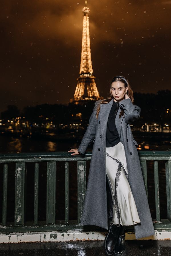Portrait of a woman in grey long coat, beige slip skirt, Eiffel Tower, Paris at night