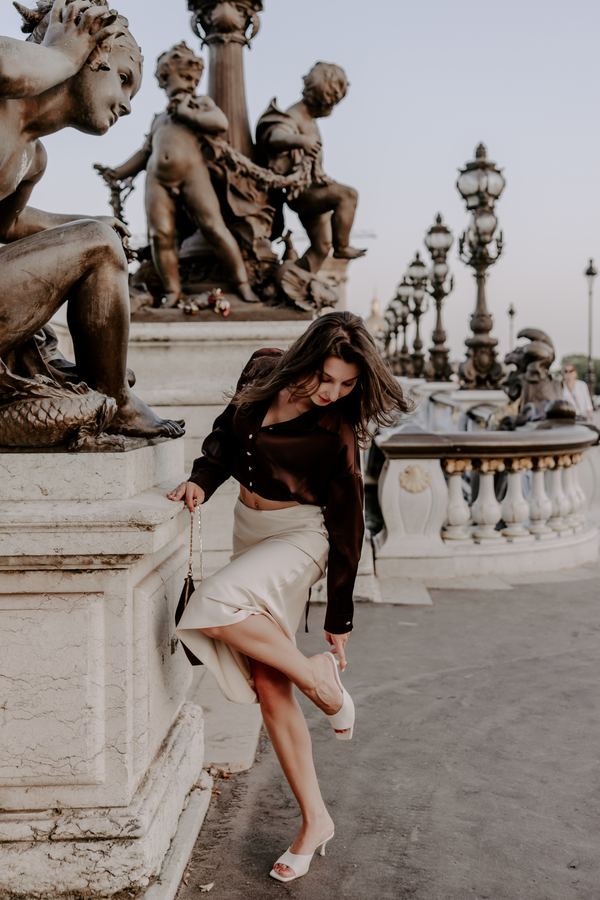 Portrait of a woman in brown satin blouse, cream skirt, Pont Alexandre III, Paris at golden hour