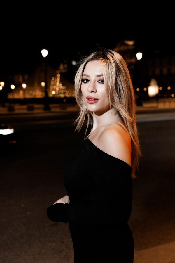 Portrait of a woman in black off-shoulder evening gown, Louvre pyramid, Paris at night